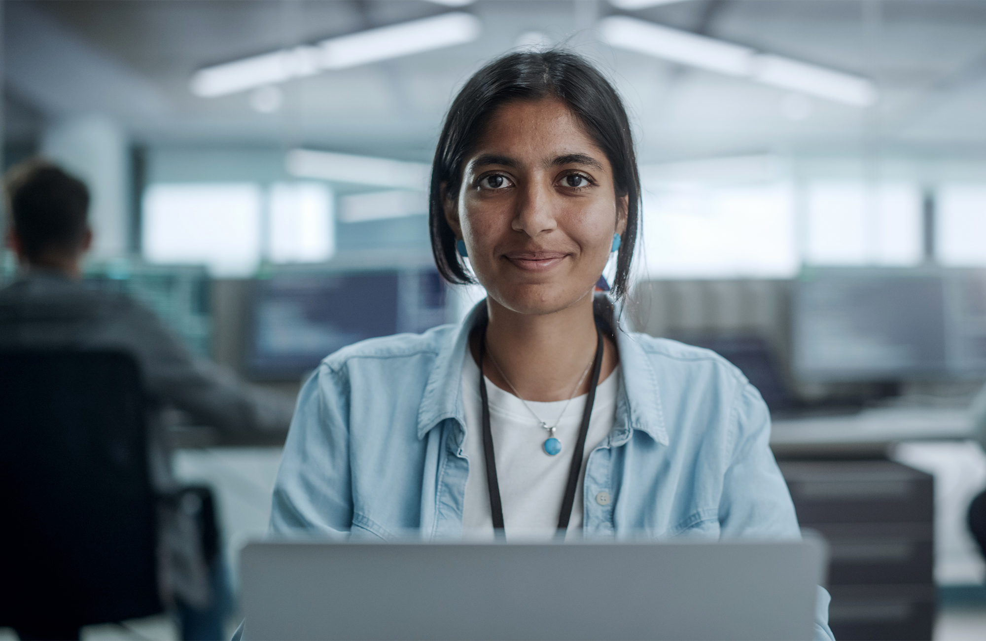 Person in a blue shirt working on a laptop in an office.